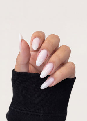 Hand with long, white-pink nails wearing a black sleeve on a light gray background